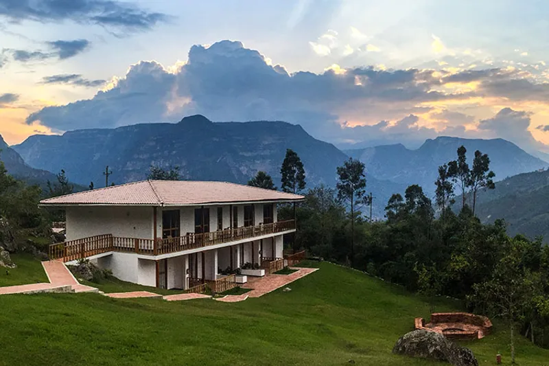 Gocta Andes Lodge on the grassy slope above Cocachimba with cloud forest ridges behind, the closest hotel to Gocta waterfall, Amazonas, Peru